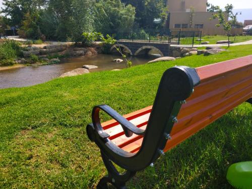a bench sitting in the grass next to a river at Cute Apartment hagoshrim in Hagoshrim