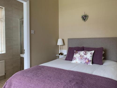 Una cama con una manta púrpura y una almohada. en Oak Lodge Portumna en Portumna