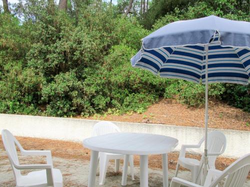 une table et des chaises blanches avec un parasol dans l'établissement Holiday Home Les Algues by Interhome, à La Tranche-sur-Mer