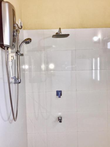 a shower in a bathroom with white tiles at Walauwa The Villa Ahungalla in Ahungalla