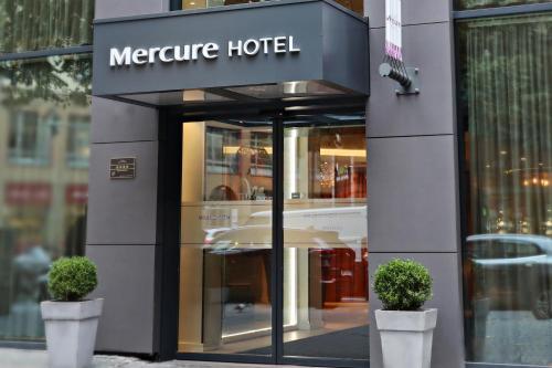 un magasin devant un hôtel de mentors avec deux plantes dans l'établissement Mercure Hotel Kaiserhof City Center, à Francfort-sur-le-Main