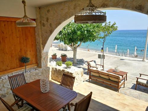 een patio met een tafel en uitzicht op het strand bij Relax Seaside House in Charaki