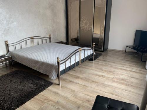 Schlafzimmer mit einem Bett, einem TV und Holzböden in der Unterkunft VirDi House in Morschyn