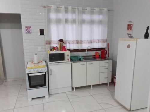 a kitchen with white cabinets and a stove and microwave at loft harmonia in Blumenau