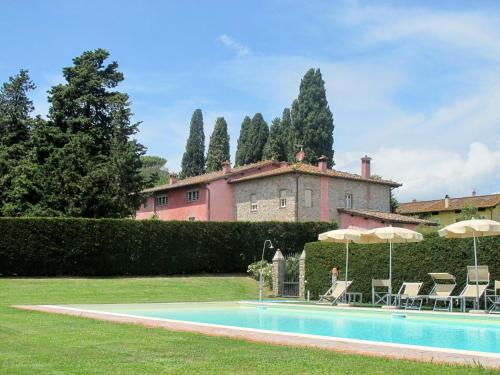 a pool with chairs and umbrellas in front of a house at Apartment Le Fornaci-1 by Interhome in San Quirico di Moriano