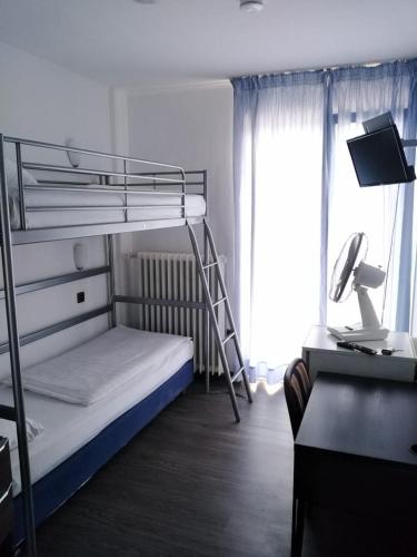 a bedroom with a bunk bed and a desk with a computer at Hotel Berliner Hof in Düsseldorf