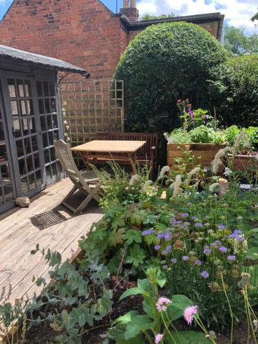 una terrazza in legno con tavolo e alcuni fiori di The Cottage a Sulgrave