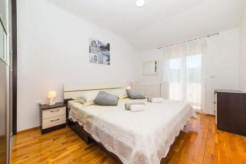 a white bedroom with a large bed and a dresser at Holiday Home Zen in Primorski Dolac