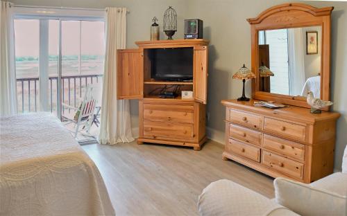 a bedroom with a bed and a dresser with a television at The Sunset Inn in Sunset Beach
