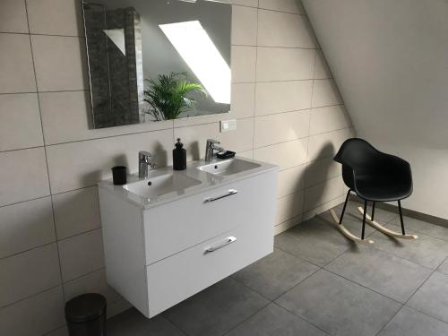 ein Badezimmer mit einem weißen Waschbecken und einem schwarzen Stuhl in der Unterkunft Maison de village in Laubach