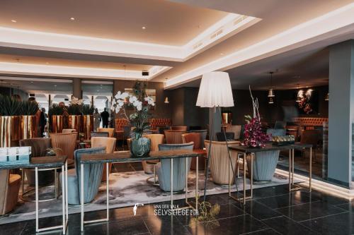 a lobby of a hotel with tables and chairs at Van Der Valk Sélys Liège Hotel & Spa in Liège