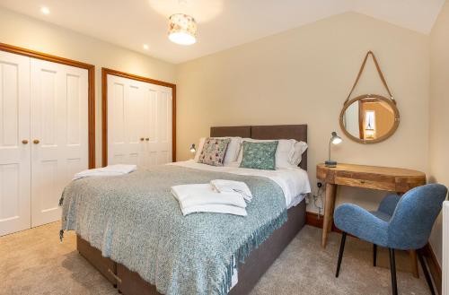 a bedroom with a bed with a blue chair and a mirror at Creamery Cottage in York