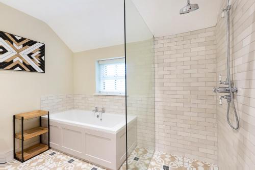een badkamer met een douche, een wit bad en een wastafel bij Creamery Cottage in York