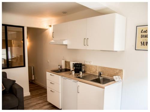 une cuisine avec des armoires blanches et un évier dans l'établissement Aventure Avignonnaise - AUTHENTIQUE - INTRAMUROS - CITY CENTER, à Avignon