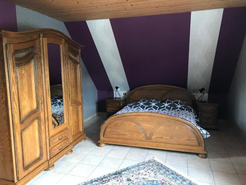 een slaapkamer met een bed en een houten kast bij Maison de village in Laubach