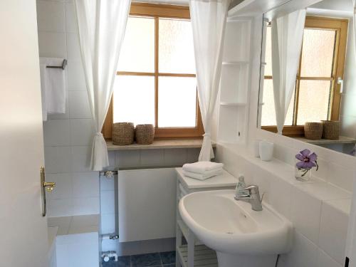 ein weißes Badezimmer mit einem Waschbecken und einem Spiegel in der Unterkunft Ferienwohnung Florina in Frasdorf