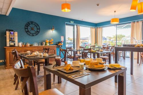 a restaurant with tables and chairs and a clock on the wall at Logis Le Cadusia in Chaource