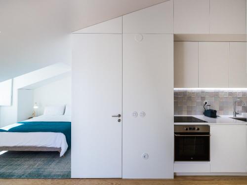 a bedroom with a bed and a kitchen with white cabinets at São Vicente 1797 Apartments in Lisbon