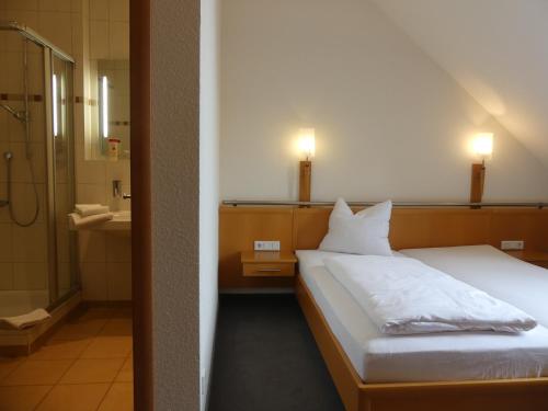 a bedroom with a bed and a bathroom with a shower at Landgasthaus Hotel Eggert in Rheine