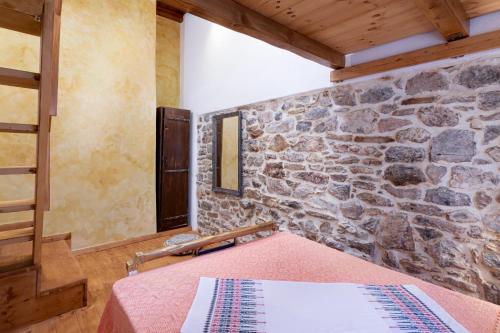 a bedroom with a stone wall and a bed at Traditional Cretan House Lithostrati Karidi Village in Karídhion