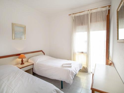 a white room with two beds and a window at PORT III Sistach Rentals in L'Estartit