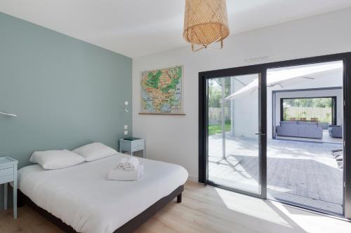 une chambre avec un lit et une porte coulissante en verre dans l'établissement Villa Epicure by Cocoonr - Belle maison proche de la plage, à Saint-Lunaire