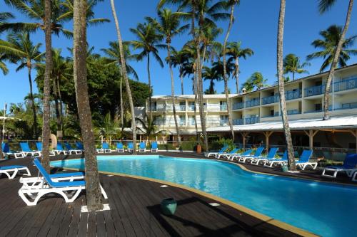 a hotel with a swimming pool and palm trees at Studio Carayou in Les Trois-Îlets
