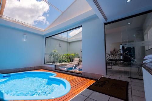 uma grande banheira de hidromassagem num quarto com uma grande janela em Motel Kalahari em Jaraguá do Sul