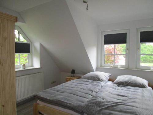 a bedroom with a bed and two windows at Landhaus von Frieling in Soltau