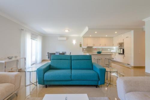 a living room with a blue couch and a kitchen at Boavista Resort - Casa Belinda in Lagos
