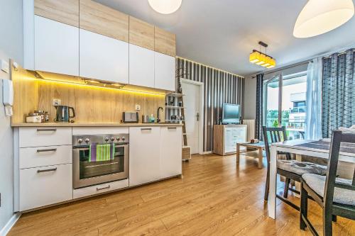 a kitchen with white cabinets and a dining room at Apartament Lemon in Pruszcz Gdański