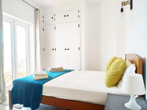 een witte slaapkamer met een groot bed met blauwe lakens bij Tavira Lovers - City Centre Apartments in Tavira