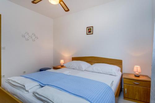 a bedroom with a bed with a blue blanket and two lamps at Apartments Anci in Mali Lošinj