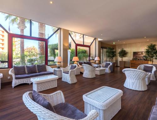 a living room with white wicker furniture and windows at Dom Pedro Marina in Vilamoura