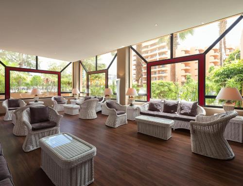 a living room with wicker furniture and large windows at Dom Pedro Marina in Vilamoura