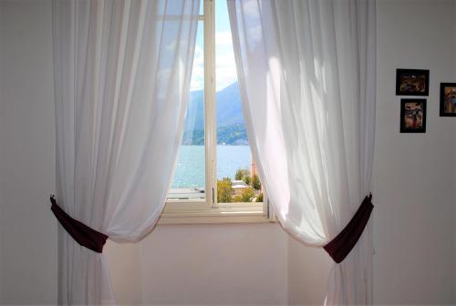 ベッラージョにあるスイートヴィラリリアの白いカーテン付きの窓、海の景色を望む