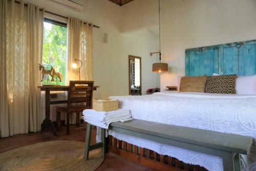 a bedroom with a bed and a table and a desk at Sunsets and Palm Trees in Alleppey