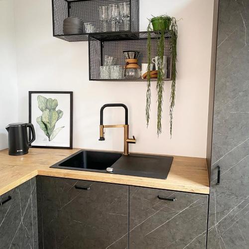 a kitchen sink with a copper faucet on a counter at Apartament Happy Loft MF in Giżycko