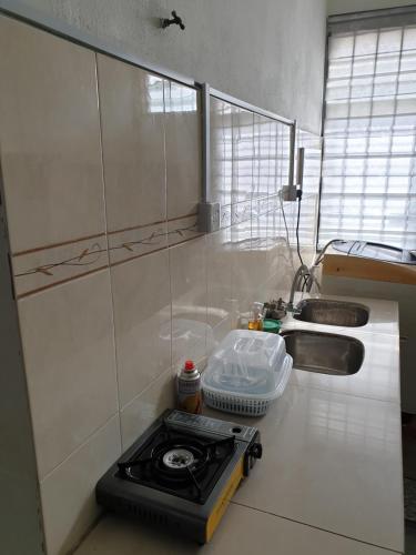 a small kitchen with a stove and a sink at Teratak Mini Pool Homestay Melaka in Melaka