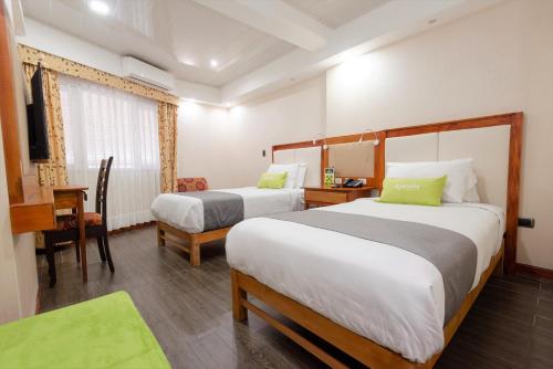 Habitación de hotel con 2 camas, escritorio y silla en Ayenda La Luna Inn, en Lima