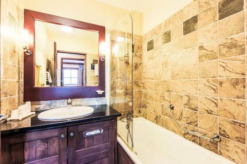 ein Badezimmer mit einer Badewanne, einem Waschbecken und einem Spiegel in der Unterkunft Appartement montagne spacieux, piscine, SPA à ARC 1950 in Arc 1950