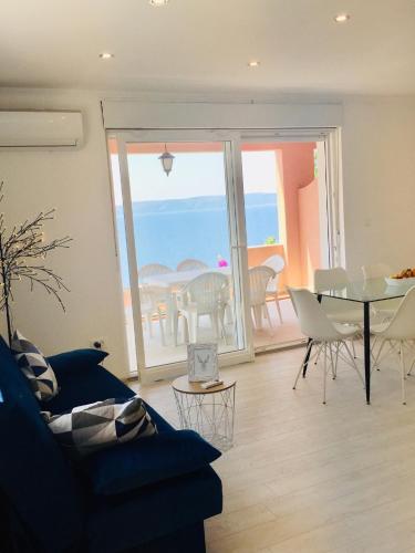 a living room with a blue couch and a table and chairs at Apartments Juraković in Živogošće