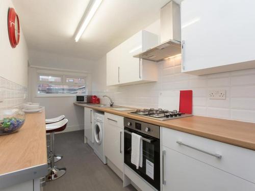 a kitchen with white cabinets and a stove top oven at TownHouse @166 Ruskin Rd in Crewe