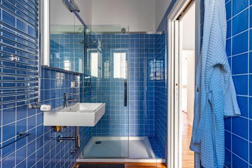 a blue tiled bathroom with a sink and a shower at Torre a mare Sun in Torre a Mare