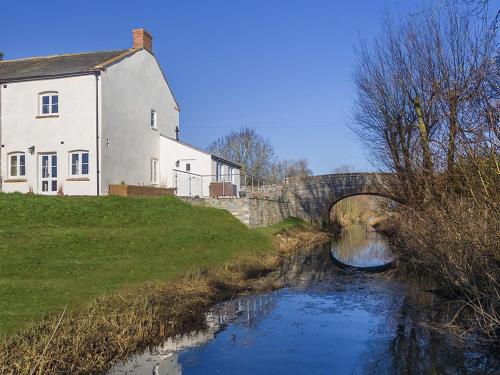 a bridge over a river next to a house at 700 Westport in Langport