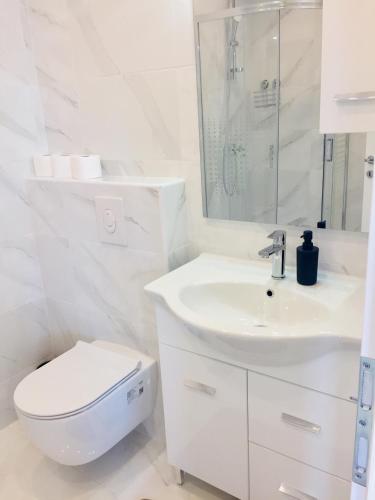 a white bathroom with a toilet and a sink at Apartments Juraković in Živogošće