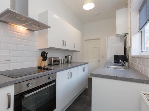 a kitchen with white cabinets and a sink at Townhouse @ 83 Edleston Road Crewe in Crewe