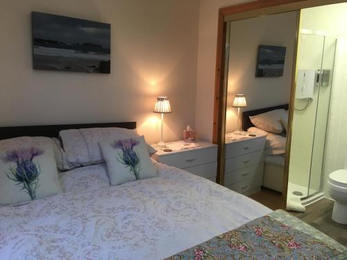 a bedroom with a bed and a bathroom with a mirror at Achmore Self catering in Achmore