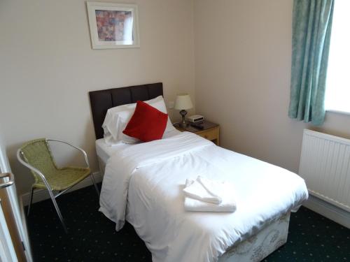 a bedroom with a bed with a red pillow and a chair at AJ Lodge in Slough