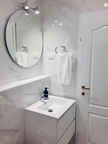 a white bathroom with a sink and a mirror at Apartments Juraković in Živogošće